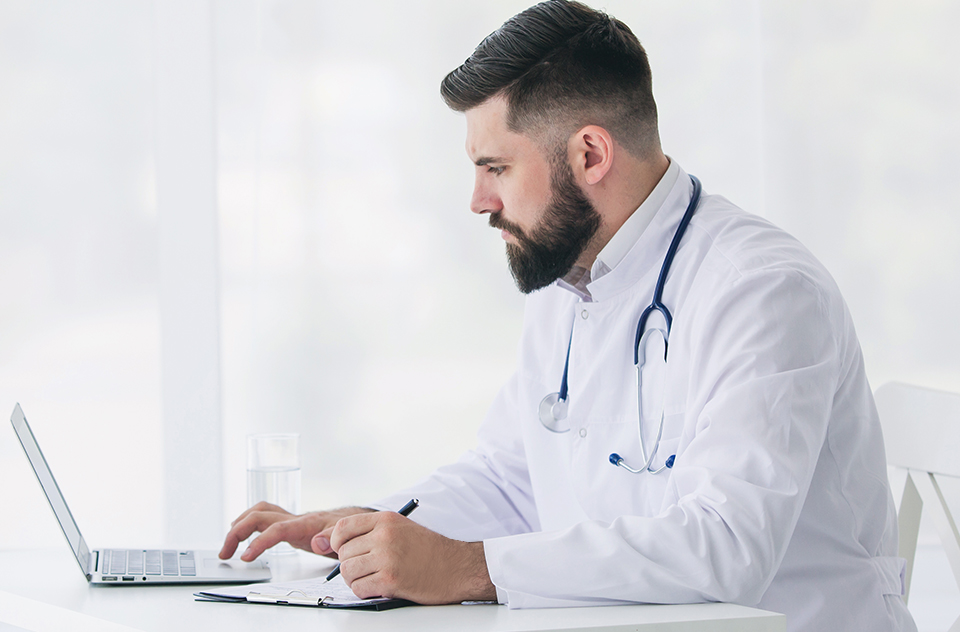 Doctor using laptop - side profile