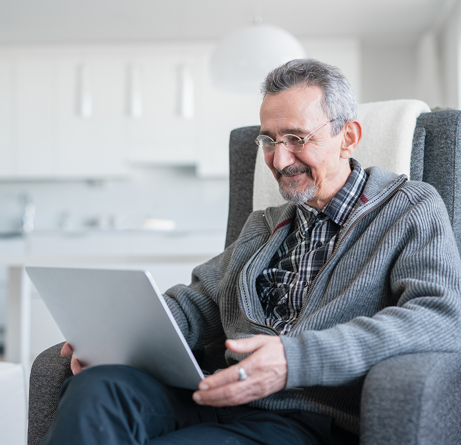 Senior sitting on sofa and using laptop